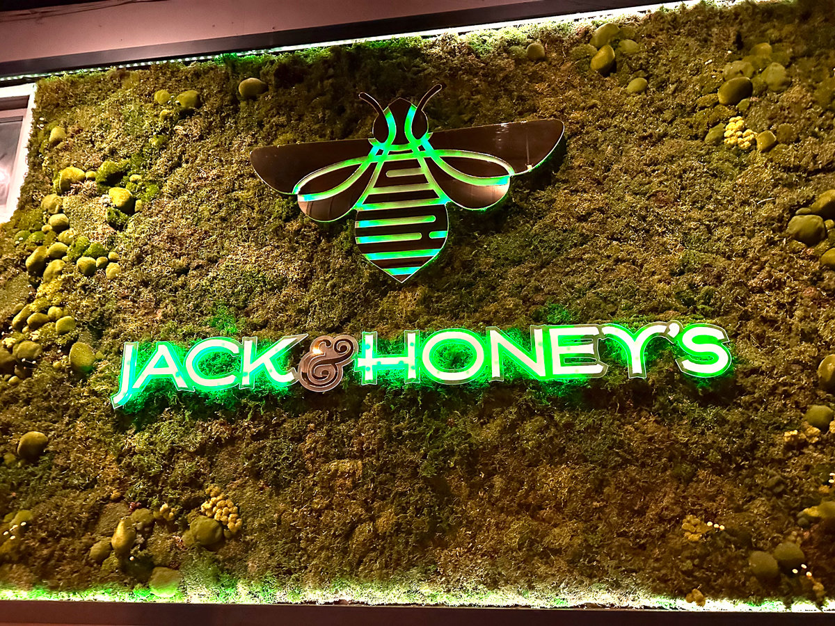 greenery wall with lit green jack and honeys sign